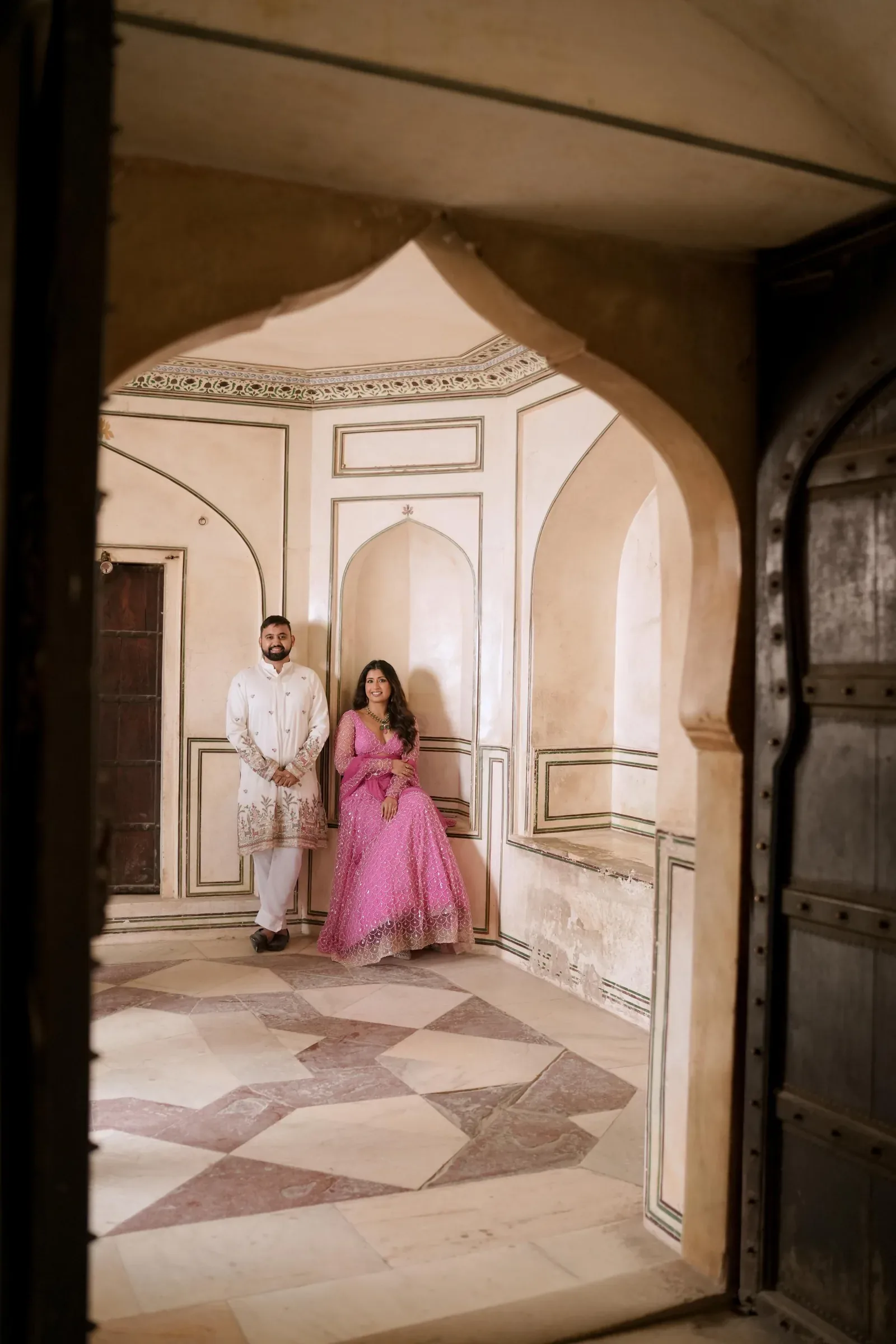 Linisha and Amit beneath a palace archway
